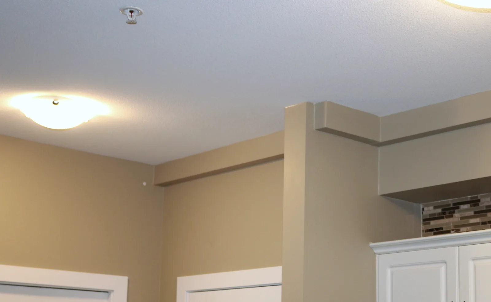 Plumbing Track enclosure turning a corner above doorways and cabinets